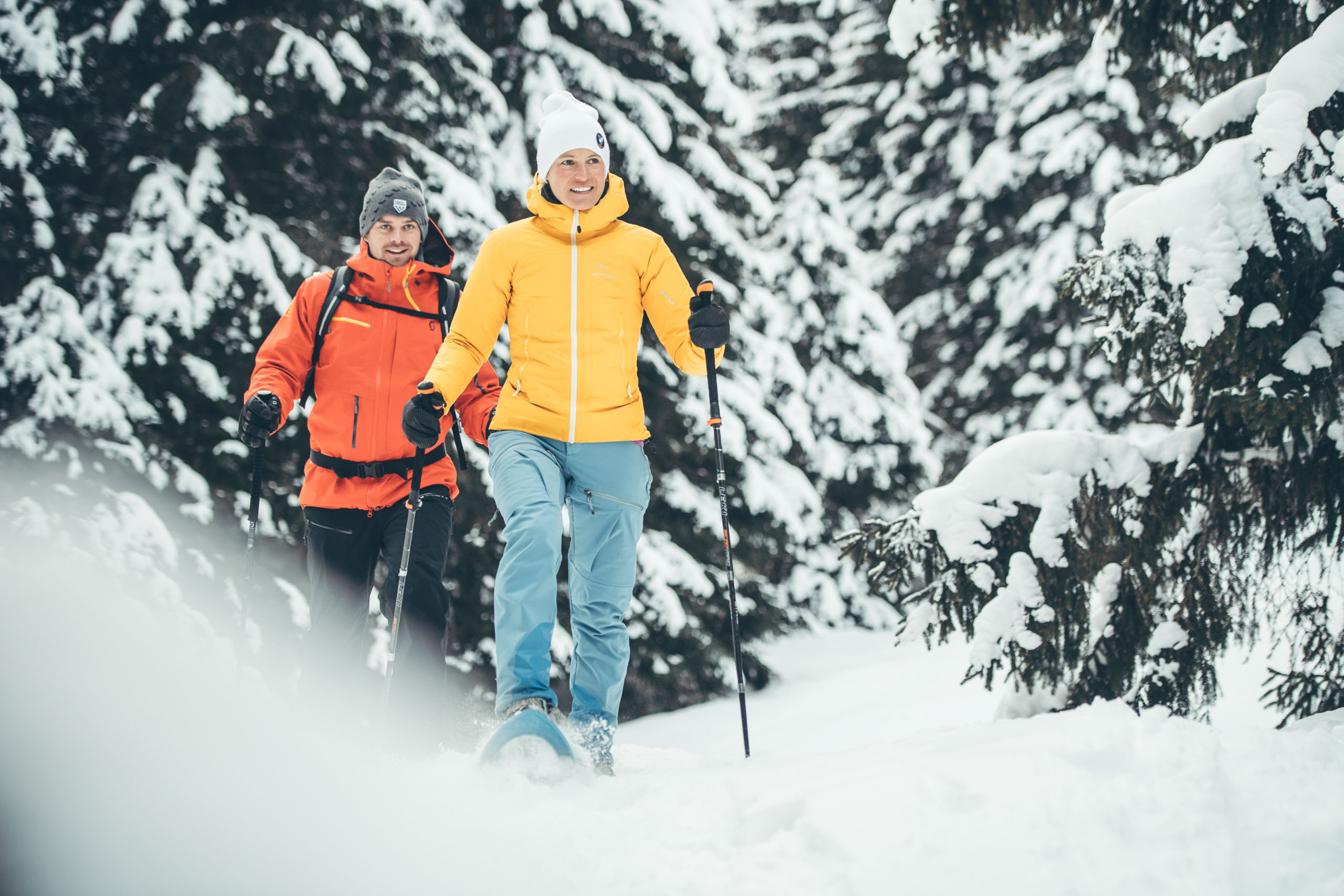 Ein Mann und eine Frau wandern mit den Schneeschuhen durch eine Winterlandschaft